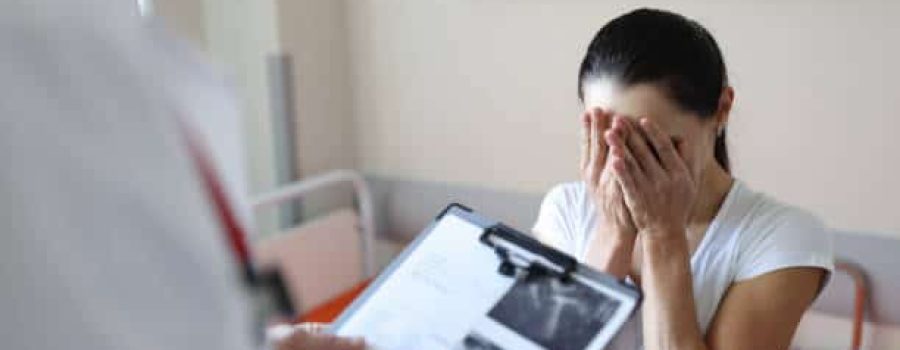 Doctor holding documents in front of crying patient in clinic. Psychological support for people with cancer concept