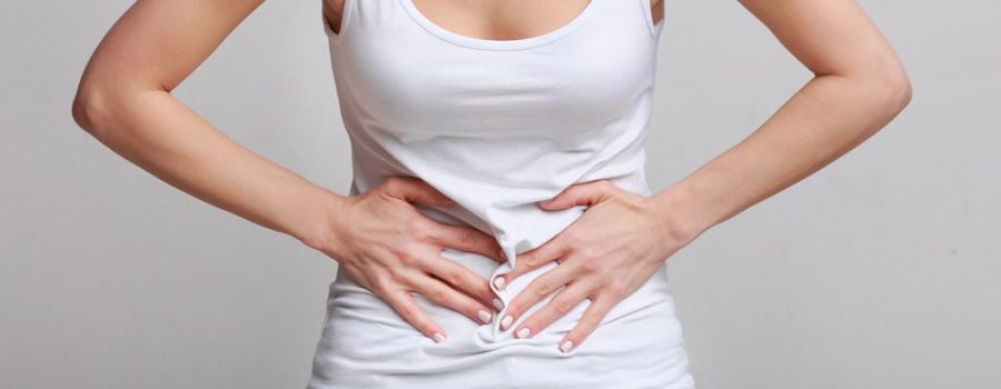 Woman with stomachache, having food poisoning or menstrual period cramp over grey background