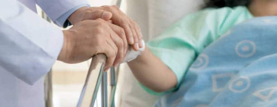 Friendly man doctor hands holding patient hand sitting at the desk for encouragement, empathy, cheering and support while medical examination. Bad news lessening, trust and ethics concept