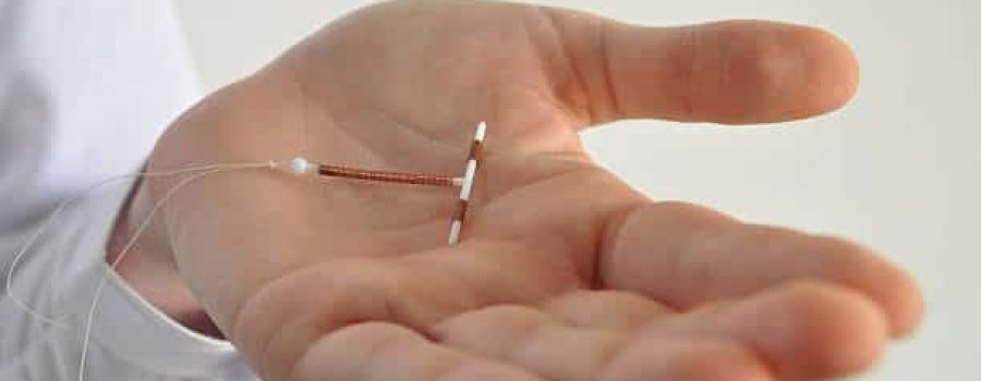 Holding an IUD birth control copper coil device in hand, used for contraception - side view